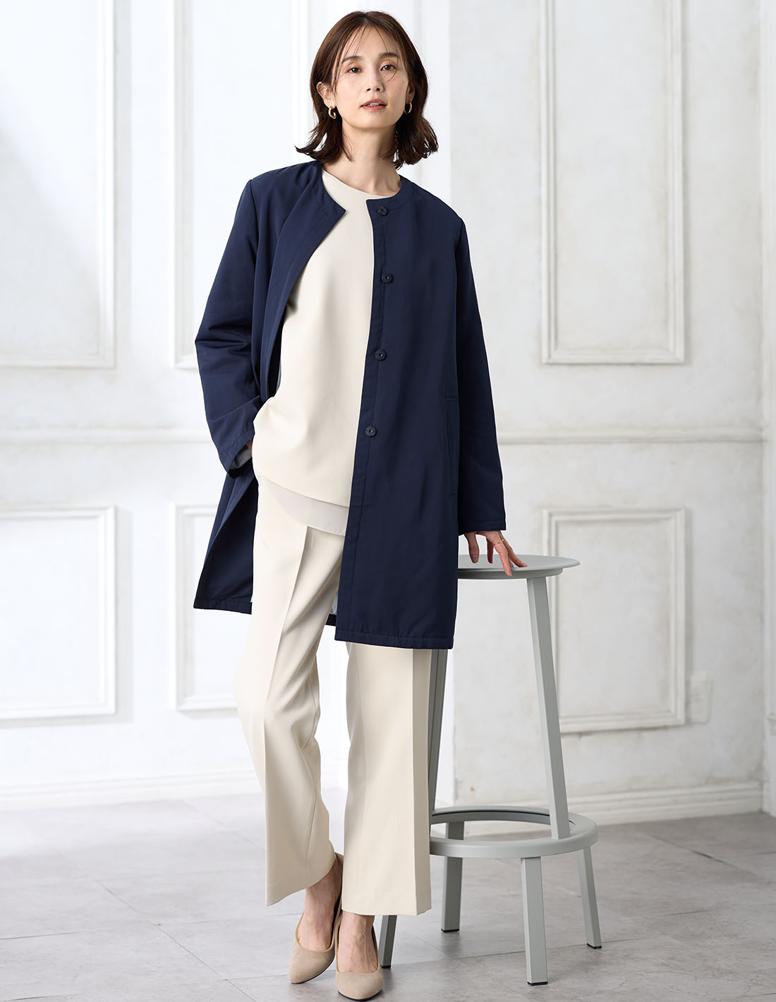 アイボリーのシフォンレイヤードブラウス【セットアップ対応】・アイボリーのストレートパンツ【セットアップ対応】・ネイビーのスーパーウォームグログランノーカラーコートを着用した女性の画像