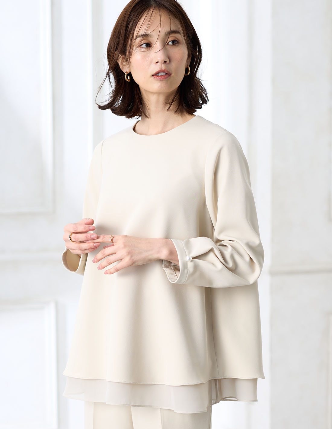 アイボリーのシフォンレイヤードブラウス【セットアップ対応】・アイボリーのストレートパンツ【セットアップ対応】を着用した女性の画像