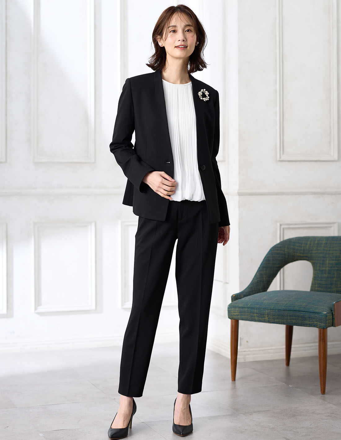 ブラックの【アルファブリック】カラーレスジャケット【セットアップ対応】・ブラックの【アルファブリック】テーパードパンツ【セットアップ対応】・ホワイトのプリーツTブラウスを着用した女性の画像--2