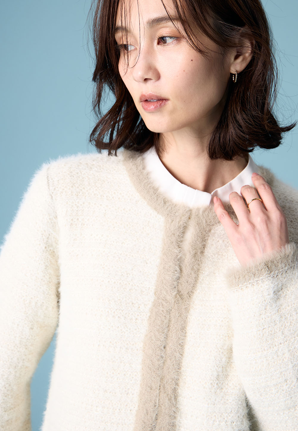 ホワイトのバイカラーニットカーディガン・ホワイトのボウタイブラウスを着用した女性の画像