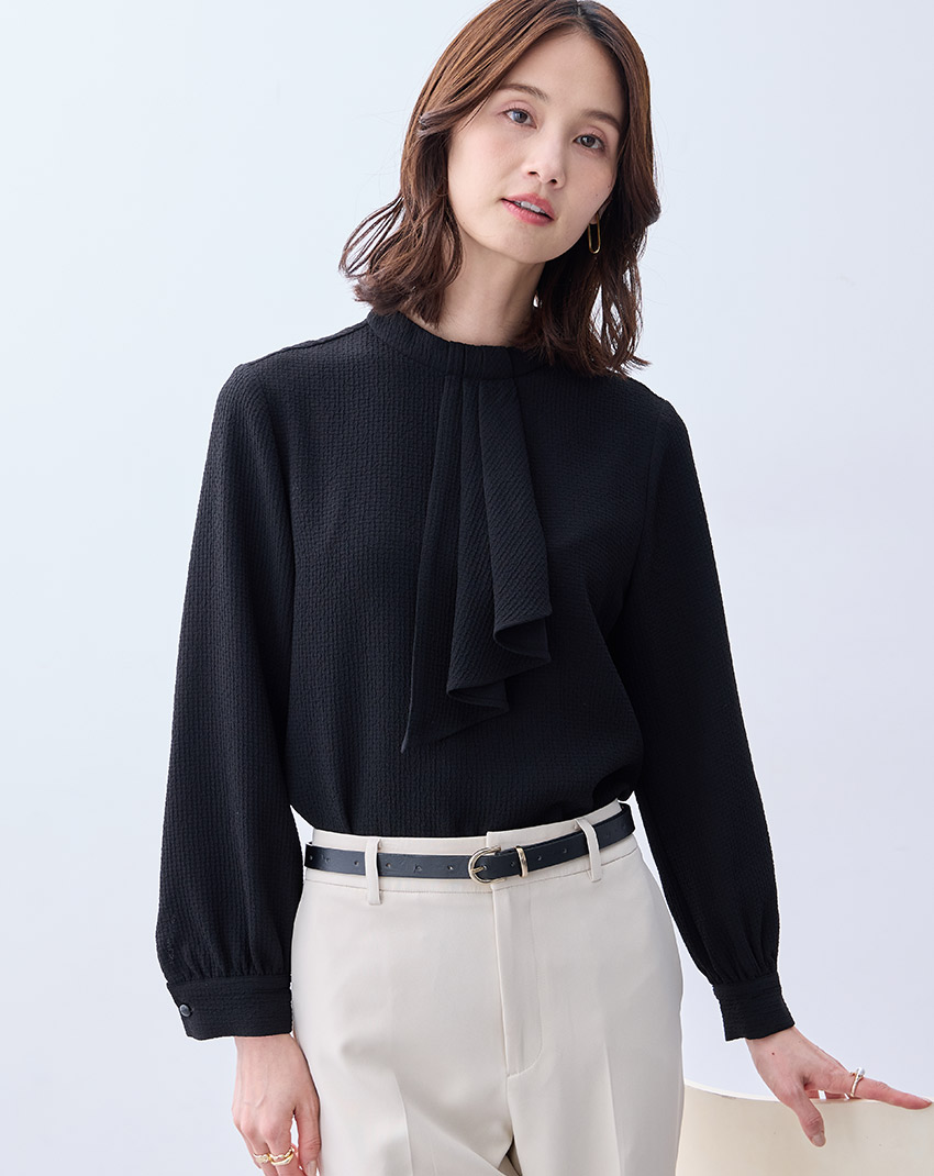 ブラックのジャガードボウタイブラウス・ベージュのストレートパンツ【セットアップ対応】を着用した女性のアップの画像