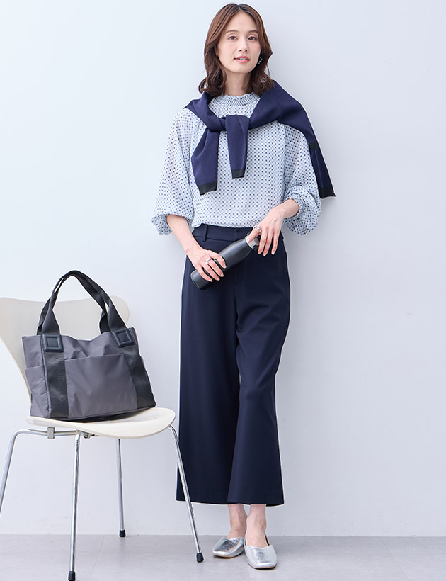 サックスブルーのジャガードTブラウス・ネイビーの【アルファブリック】ワイドパンツ【セットアップ対応】・ネイビーのバイカラーニットカーディガン【ハンドウォッシャブル】・チャコールグレーの軽量A4トートバッグを着用した女性の画像
