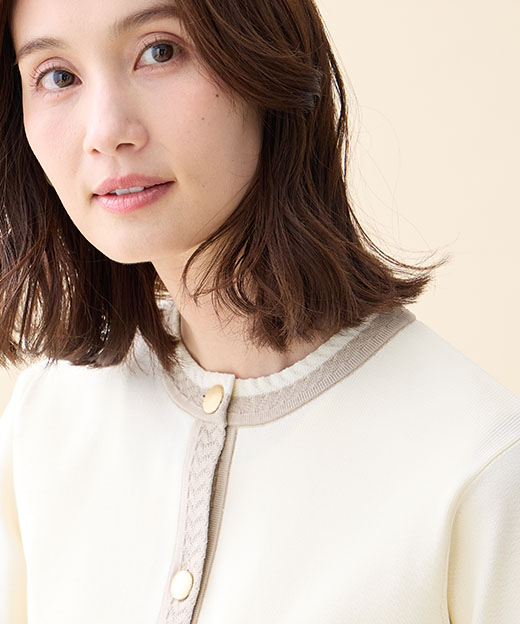 オフホワイトのバイカラーニットカーディガンを着用した女性の画像（ポイント）