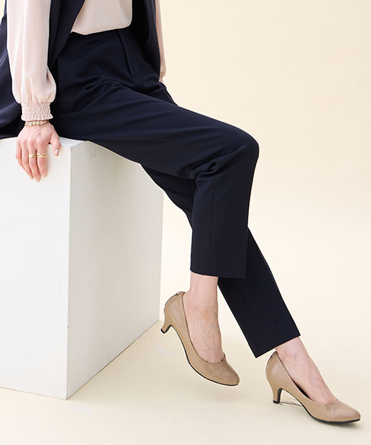 ネイビーのジレジャケット・ピンクのフリルブラウス・ネイビーの【アルファブリック】テーパードパンツを着用した女性の足元の画像（ポイント）