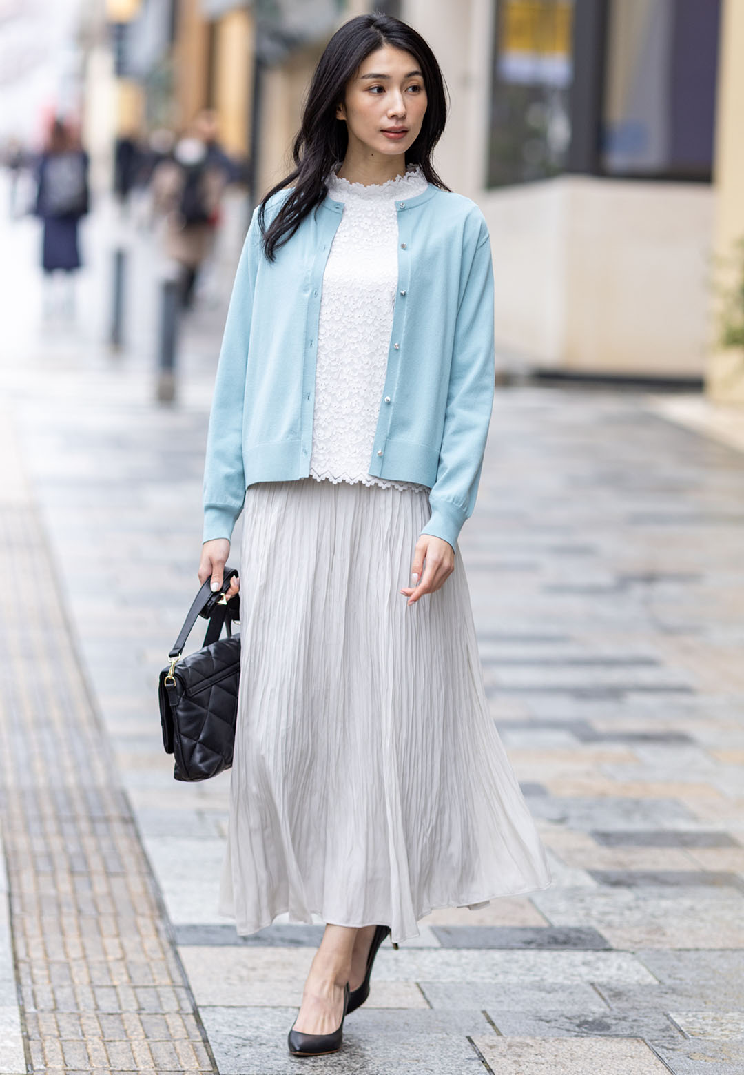 オフホワイトのフロントレースハイネックプルオーバー・ミントグリーンのクルーネックニットカーディガン・ベージュのプリーツスカートを着用した女性の画像--1