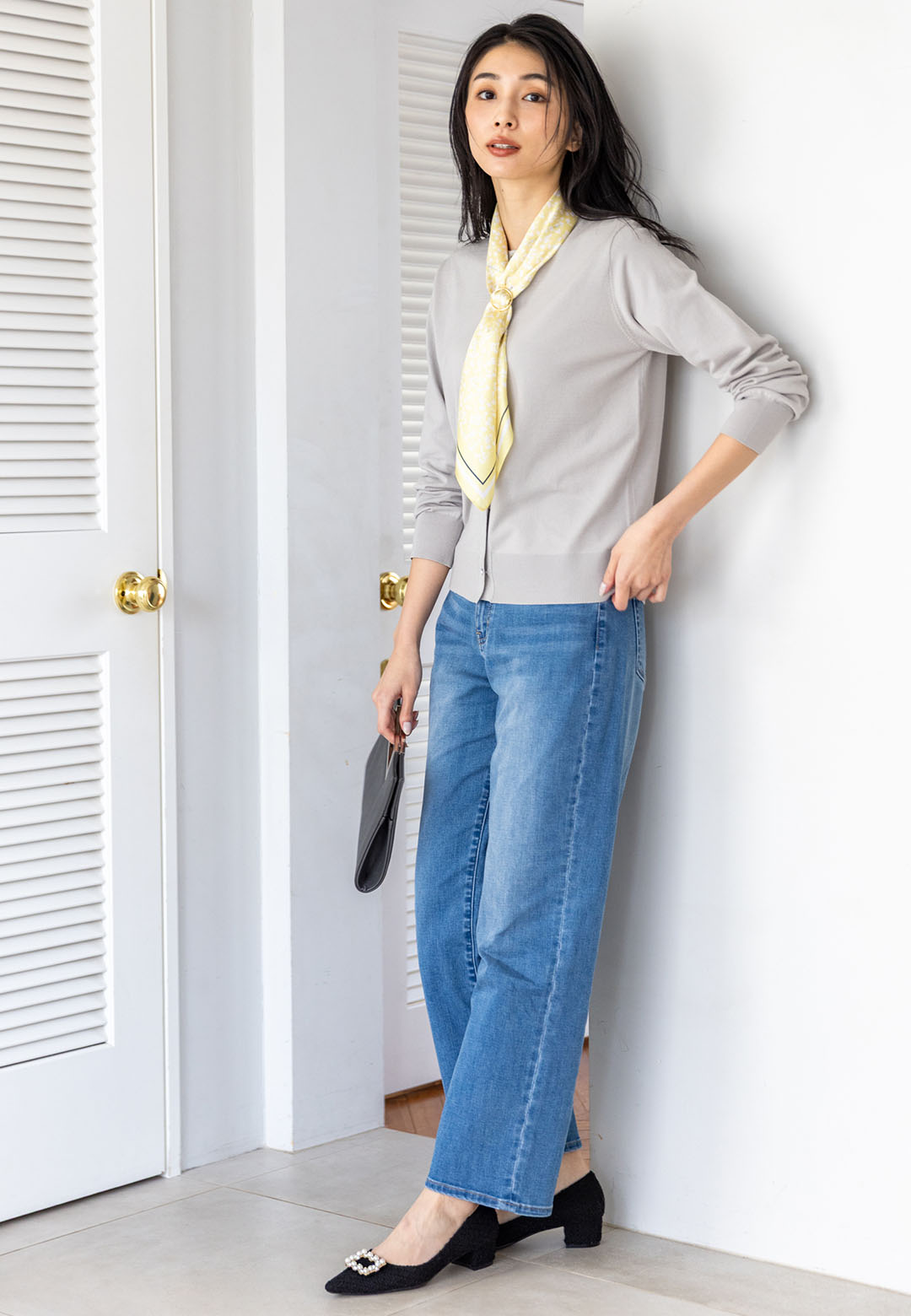 ライトグレーのクルーネックニットカーディガン・ブルーのデニムパンツ・イエローのリング付きスカーフを着用した女性の画像--2