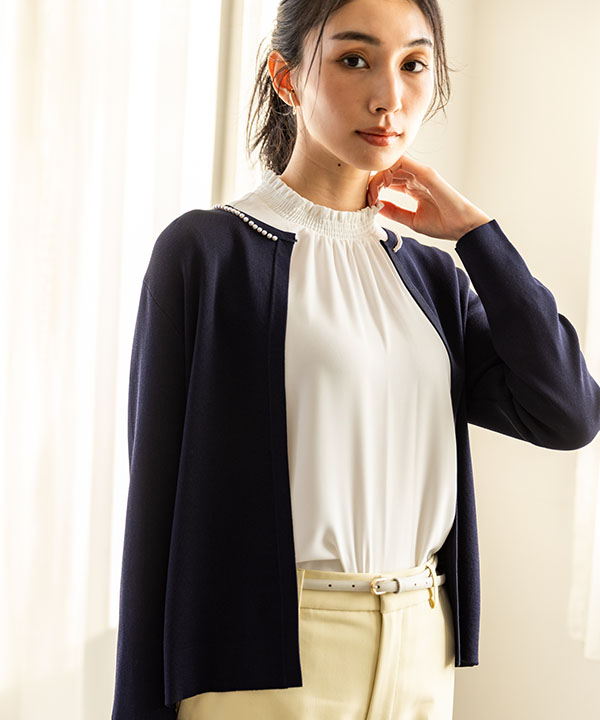 ネイビーのパールボタンニットカーディガン・オフホワイトのフリルブラウス・パステルイエローのストレッチ テーパードパンツを着用した女性の画像（アンカーリンク）