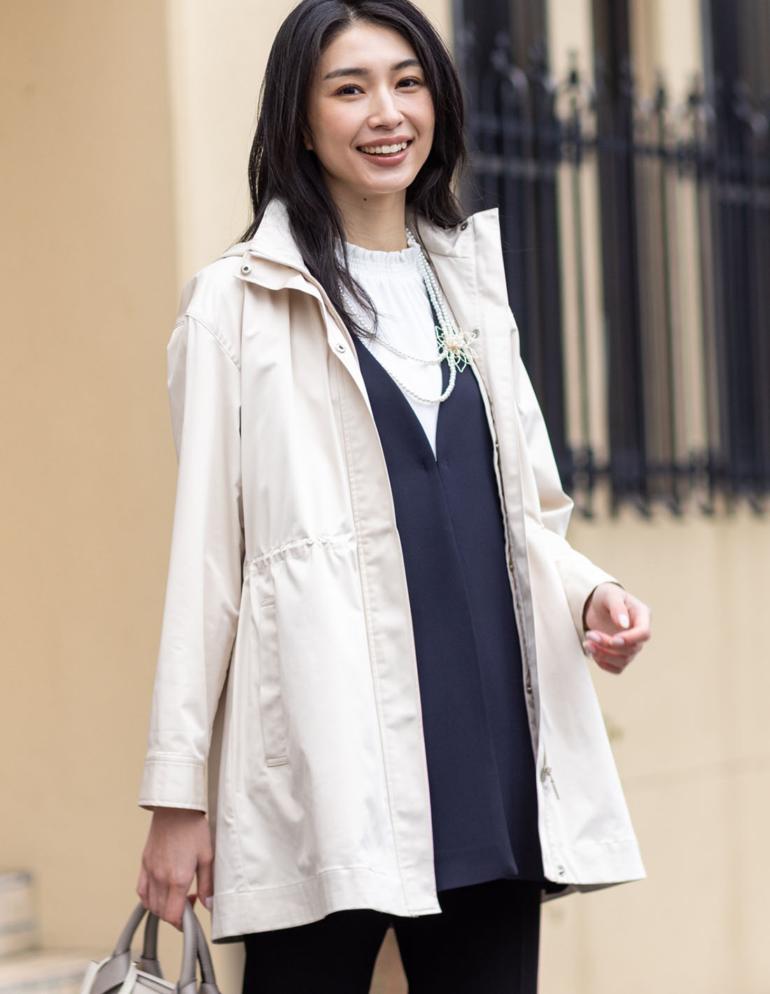 ベージュのキルトライナーコート・ネイビーのジレジャケット【セットアップ対応】・オフホワイトのフリルブラウス・ネイビーのストレッチストレートパンツ【セットアップ対応】を着用した女性の画像--1