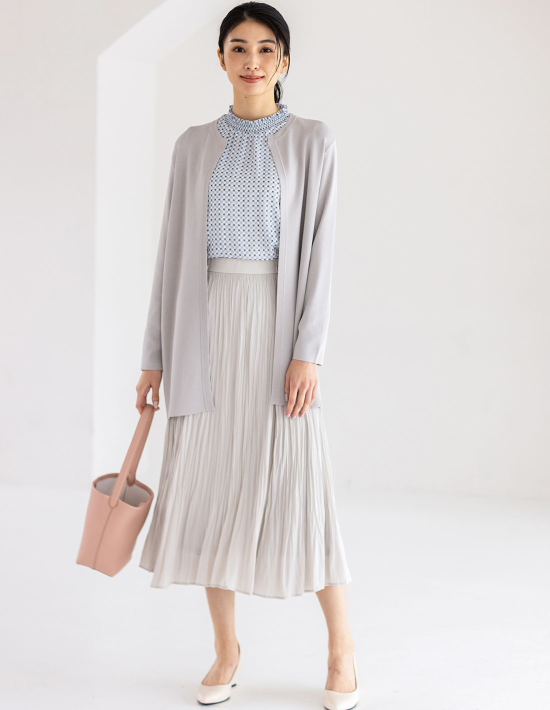 ライトグレーのクルーネックニットロングカーディガン・サックスのジャガードTブラウス・ベージュのプリーツスカートを着用した女性の画像--2