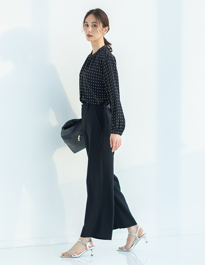 ブラックの幾何プリントジョーゼットブラウス・ブラックのストレッチジョーゼットストレートパンツ【セットアップ対応】・軽量2WAYバッグを着用した女性の画像