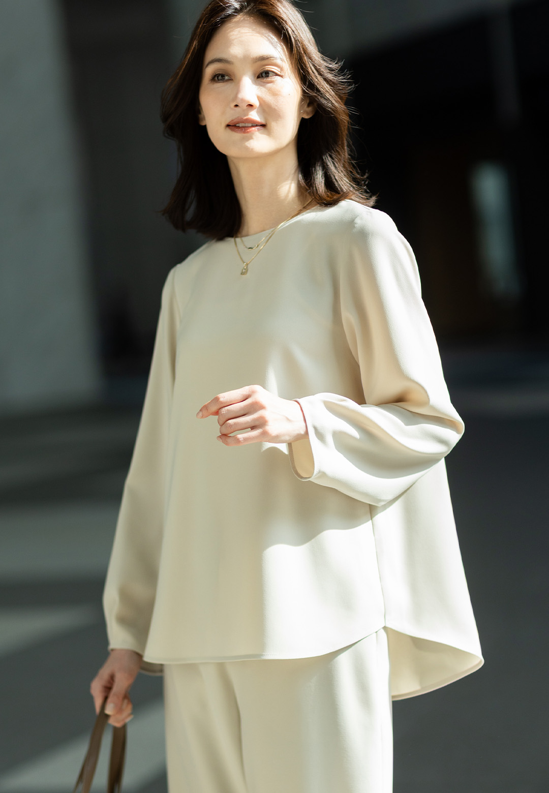 ストレッチジョーゼットタックブラウス【セットアップ対応】、ストレッチジョーゼットストレートパンツ【セットアップ対応】、編み込み風合皮トートバッグを着用した女性の画像--2