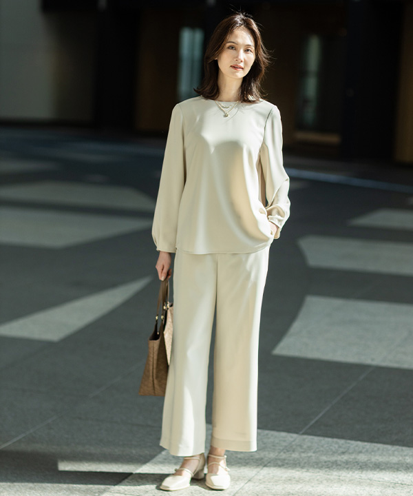 ストレッチジョーゼットタックブラウス【セットアップ対応】、ストレッチジョーゼットストレートパンツ【セットアップ対応】、編み込み風合皮トートバッグを着用した女性の画像（アンカーリンク）