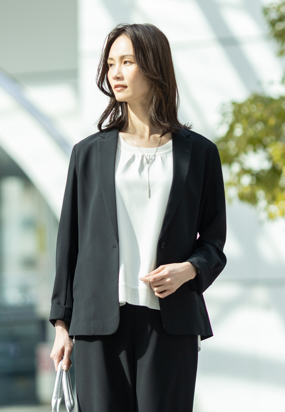 ストレッチジョーゼットテーラードジャケット【セットアップ対応】、ストレッチジョーゼットストレートパンツ【セットアップ対応】、Ｖモチーフネックレスを着用した女性の画像--1