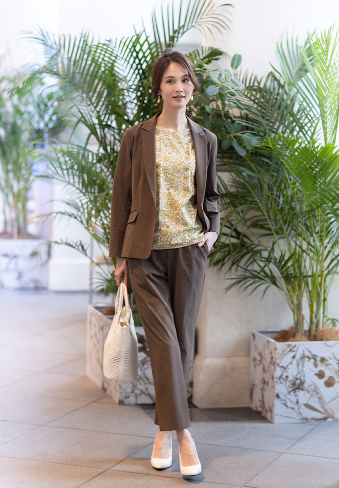 リバティプリントプルオーバー、ストレッチテーラードジャケット、ストレッチストレートパンツを着用した女性の全身画像