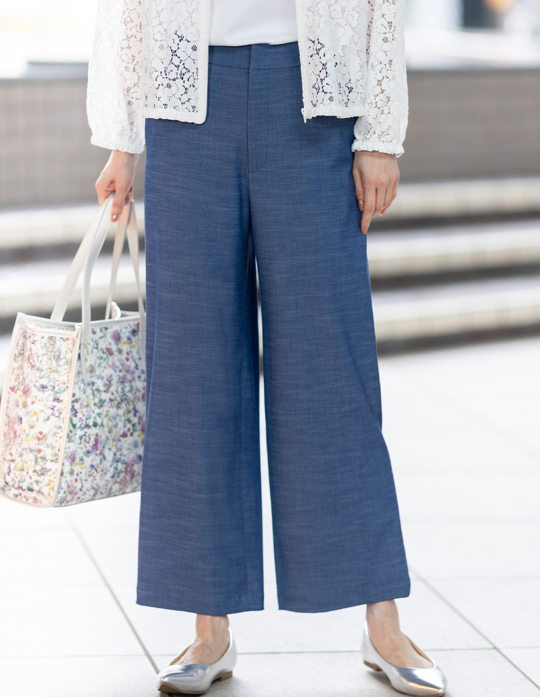 ブルーのデニムライクストレッチワイドパンツ・ホワイトのレースシアーブルゾン・ホワイトのクルーネックTシャツ【すごツヤ・UVカット・接触冷感】・リバティプリントトートバッグを着用した女性の足元