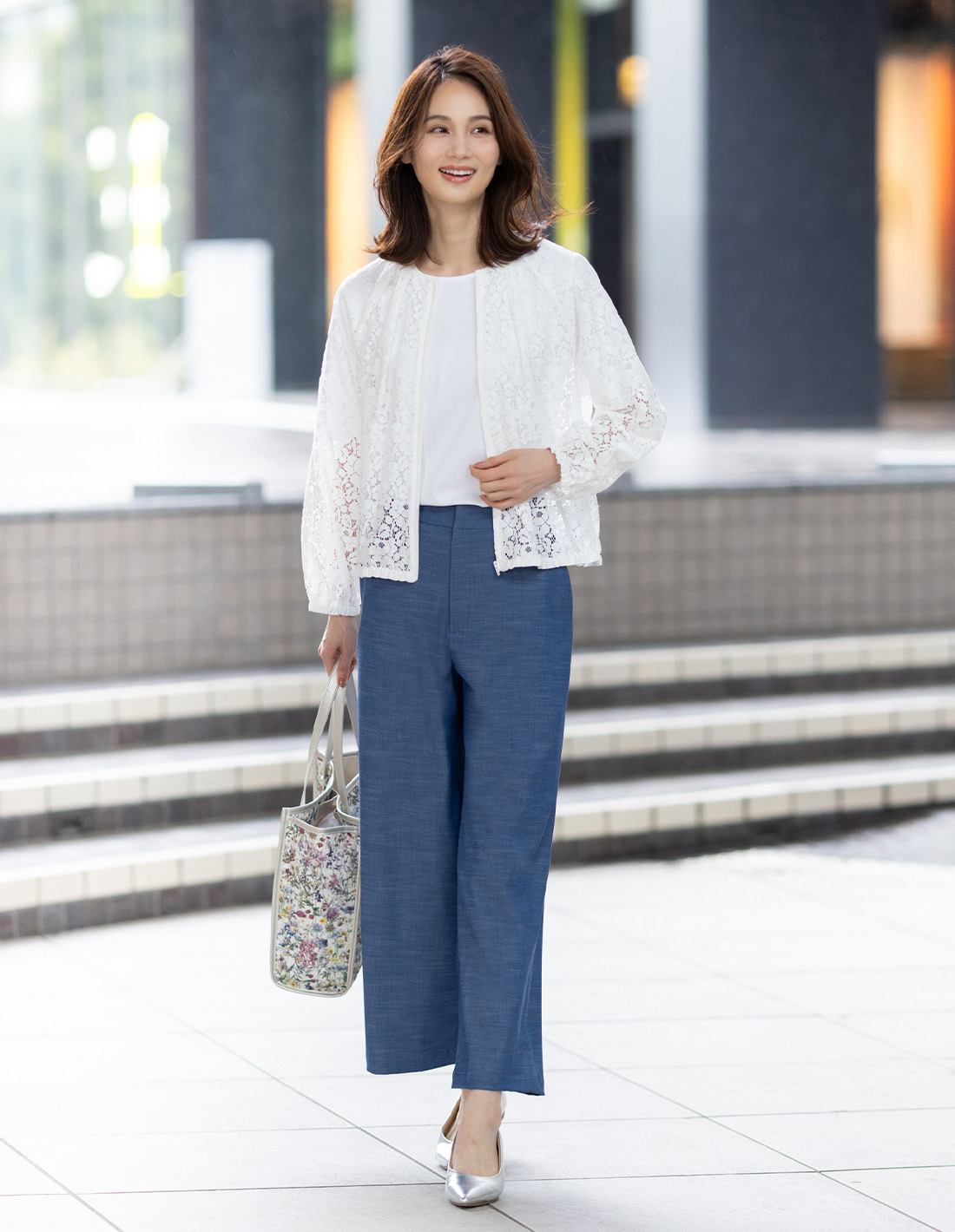 ブルーのデニムライクストレッチワイドパンツ・ホワイトのレースシアーブルゾン・ホワイトのクルーネックTシャツ【すごツヤ・UVカット・接触冷感】・リバティプリントトートバッグを着用した女性