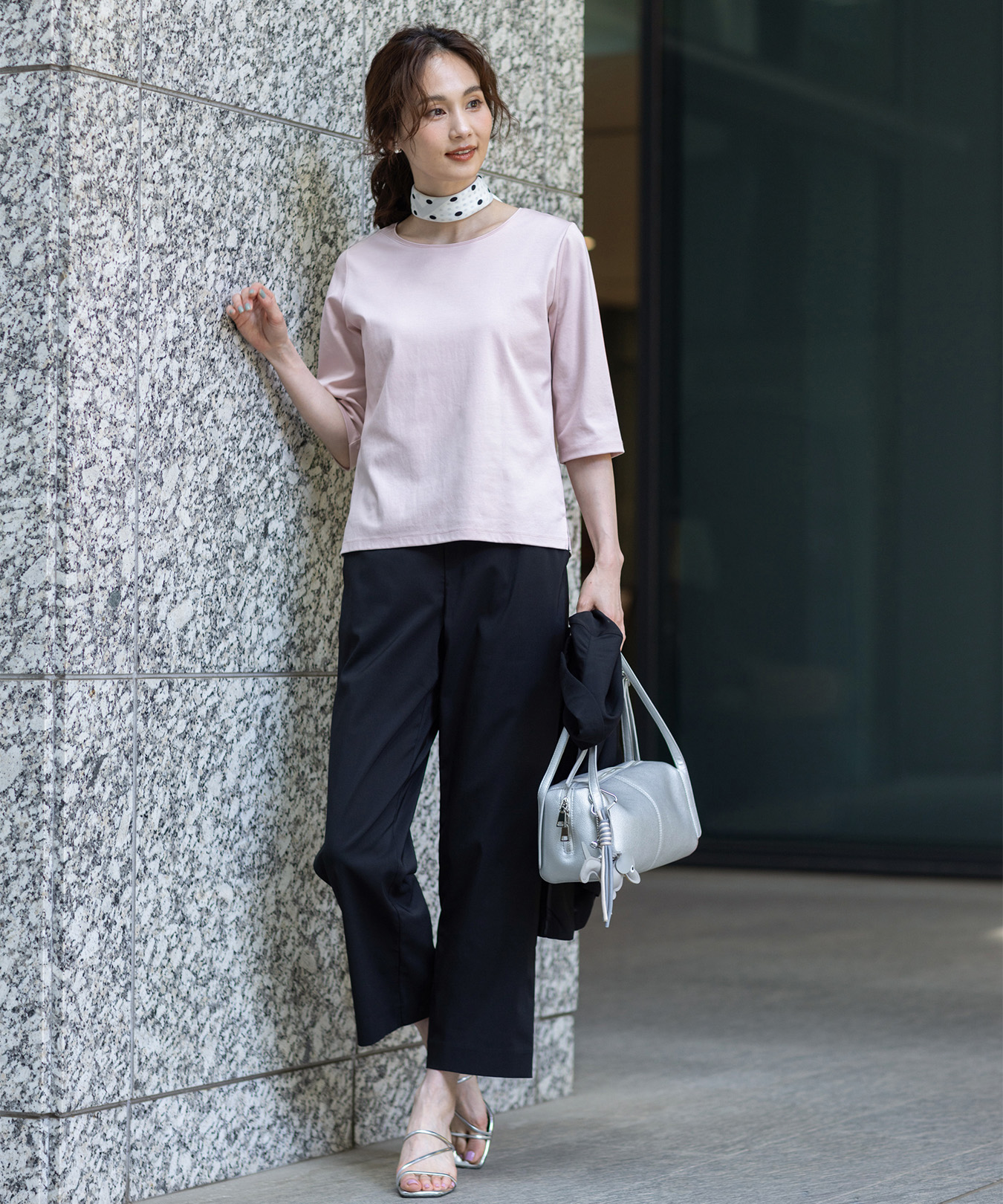 スムースカットソー、ストレッチストレートパンツ、ドッグモチーフチャームを付けた鞄を着用した女性の画像
