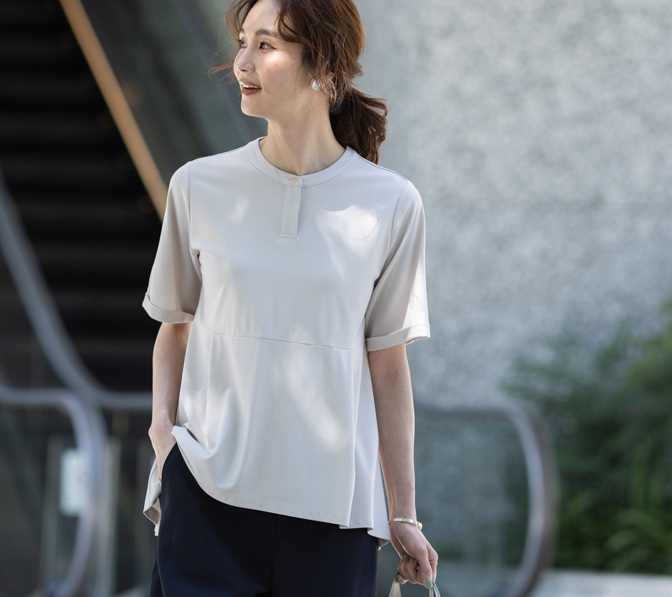 ベージュ色のクルーネックペプラムTシャツ、リネンライクセミワイドパンツを着用した女性の画像