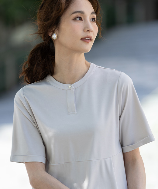 ベージュ色のクルーネックペプラムTシャツを着用した女性のアップの画像（ポイント）