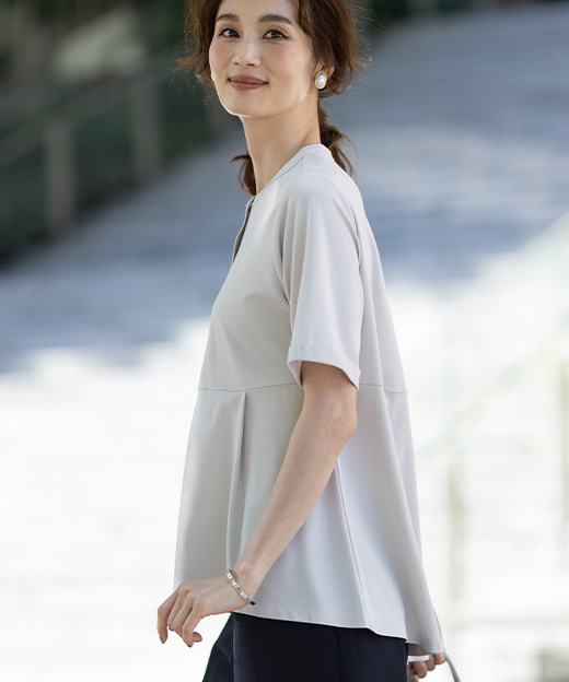 ベージュ色のクルーネックペプラムTシャツ、リネンライクセミワイドパンツを着用した女性の横姿の画像（ポイント）