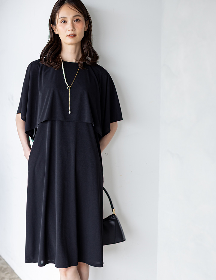 ブラックのケープスリーブワンピースを着用した女性--1