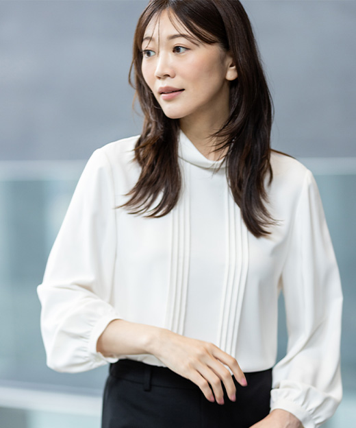 白いブラウスを着用し、左斜め前を向いている女性