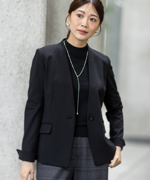 グレーのワイドパンツ・ブラックのトップス・ブラックのジャケットを着用し、左斜め前を見ている女性