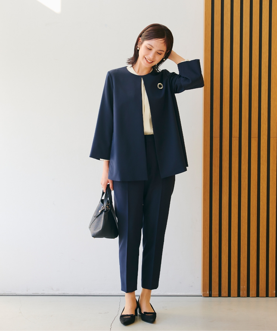 ネイビーの《洗える・シワになりにくい》正解Aラインフレアジャケット・ネイビーの《洗える・シワになりにくい》正解テーパードパンツ・オフホワイトの《シワになりにくい》シルキーサテン2WAYタックブラウスを着用した女性の画像