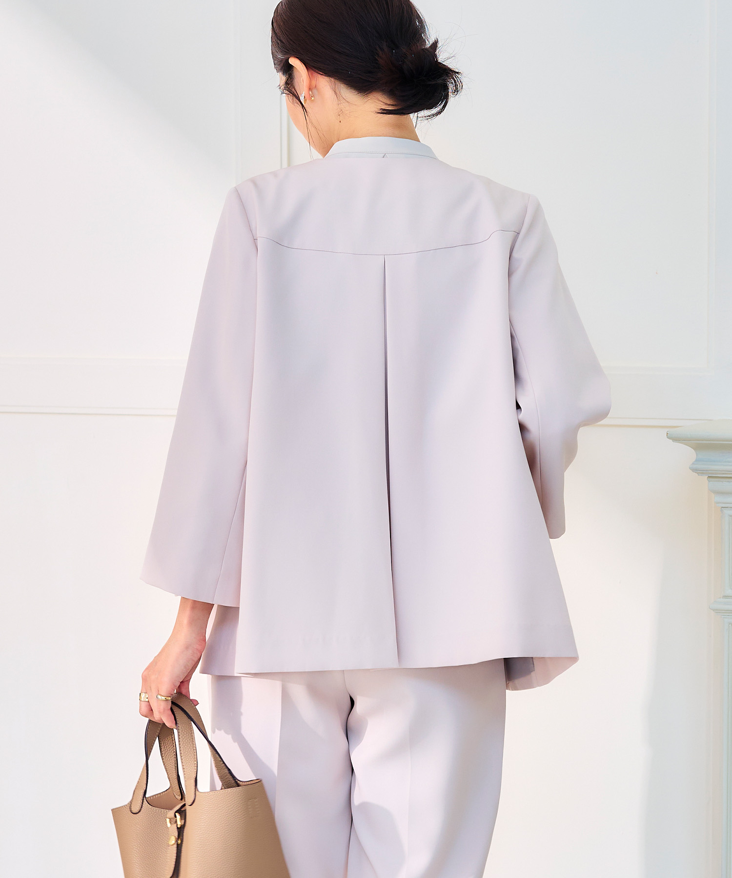 オフベージュの《洗える・シワになりにくい》正解Aラインフレアジャケット・オフベージュの《洗える・シワになりにくい》正解テーパードパンツ・オフホワイトの《シワになりにくい》シルキーサテンパールボウタイブラウスを着用した女性の画像（スライド）