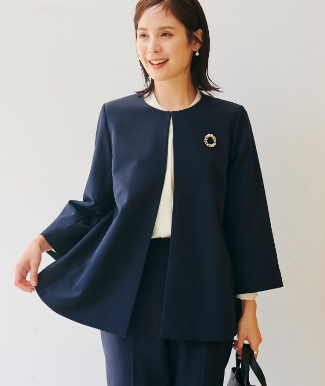 ネイビーの《洗える・シワになりにくい》正解Aラインフレアジャケット・ネイビーの《洗える・シワになりにくい》正解テーパードパンツ・オフホワイトの《シワになりにくい》シルキーサテン2WAYタックブラウスを着用した女性の画像（サムネイル）