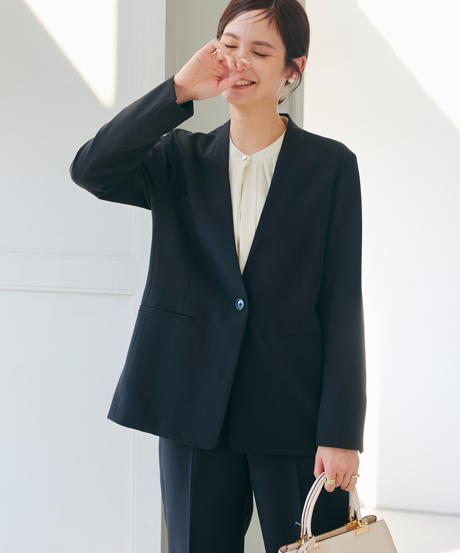 ブラックの《洗える・シワになりにくい》正解ノーカラージャケット・ブラックの《洗える・シワになりにくい》正解ワイドパンツ・オフホワイトの《シワになりにくい》シルキーサテン2WAYタックブラウスを着用した女性の画像（サムネイル）