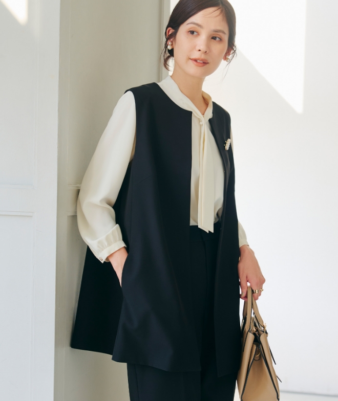 ブラックの《洗える・シワになりにくい》正解ロングジレ・ブラックの《洗える・シワになりにくい》正解ワイドパンツ・オフホワイトの《シワになりにくい》シルキーサテンパールボウタイブラウスを着用した女性の画像（サムネイル）