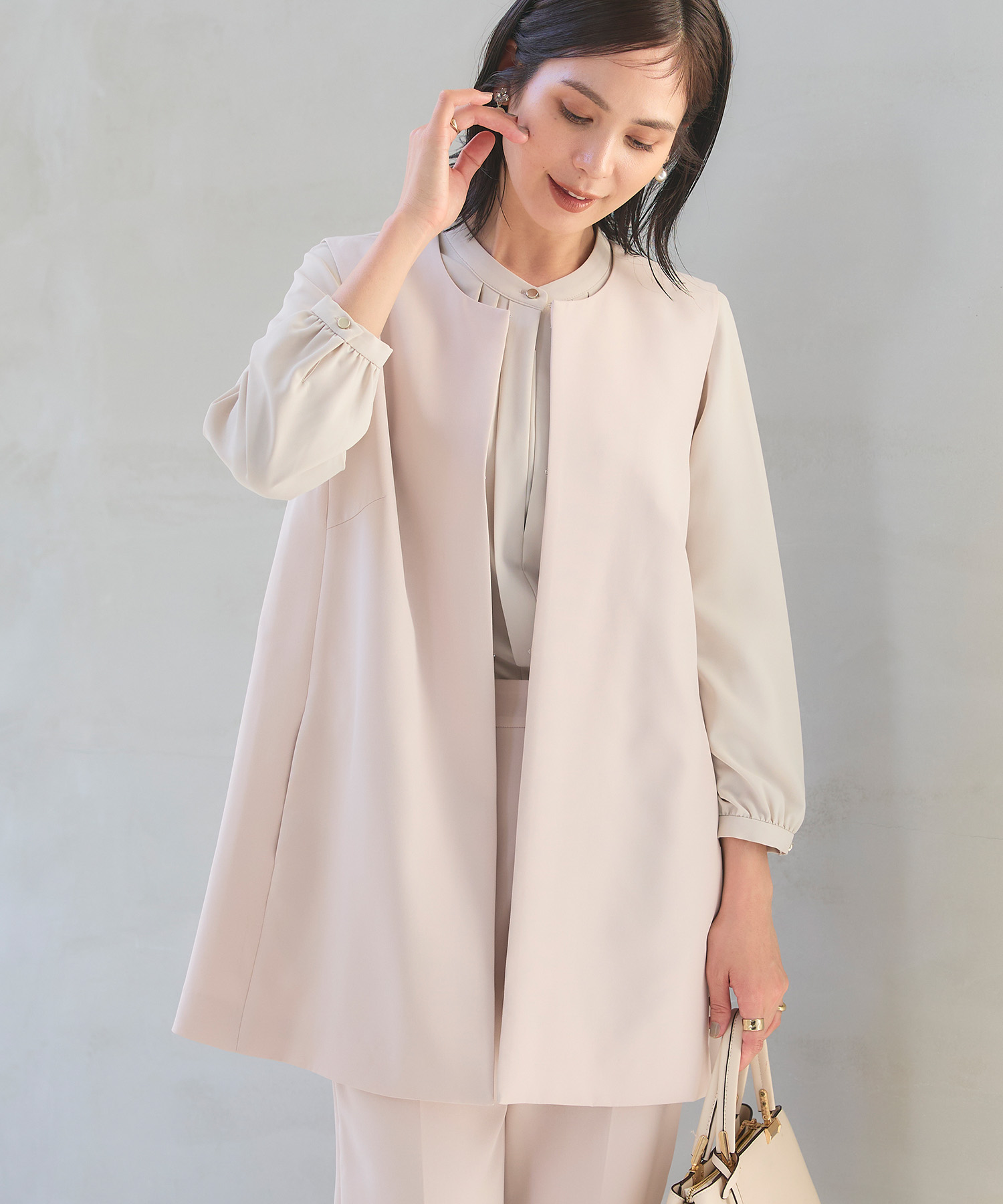 オフベージュの《洗える・シワになりにくい》正解ロングジレ・オフベージュの《洗える・シワになりにくい》正解ワイドパンツ・ライトベージュの《シワになりにくい》シルキーサテン2WAYタックブラウスを着用した女性の画像（サムネイル）