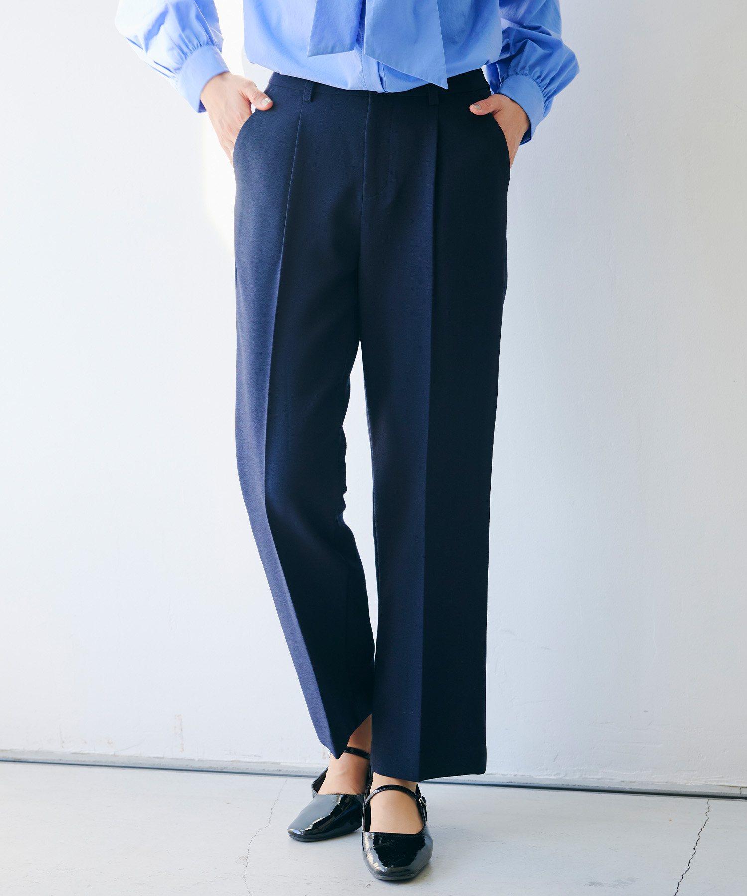ネイビーの《洗える・シワになりにくい》正解 センタープレスストレートパンツ・ブルーの《シワになりにくい》リボンボウタイボリュームシャツを着用した女性の足元の画像（スライド）