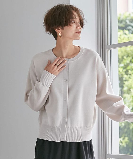 スナップボタンニットカーディガンのオフベージュを着用している女性の写真