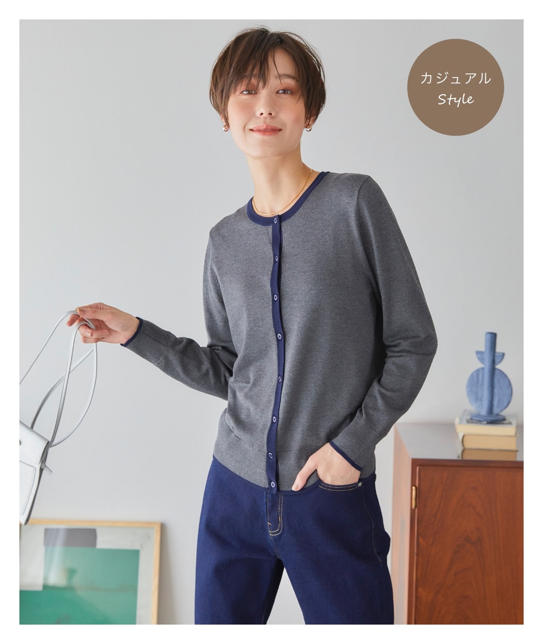 バイカラークルーネックカーディガンを着用した女性が片手にバッグを持っている写真（カジュアルStyle）