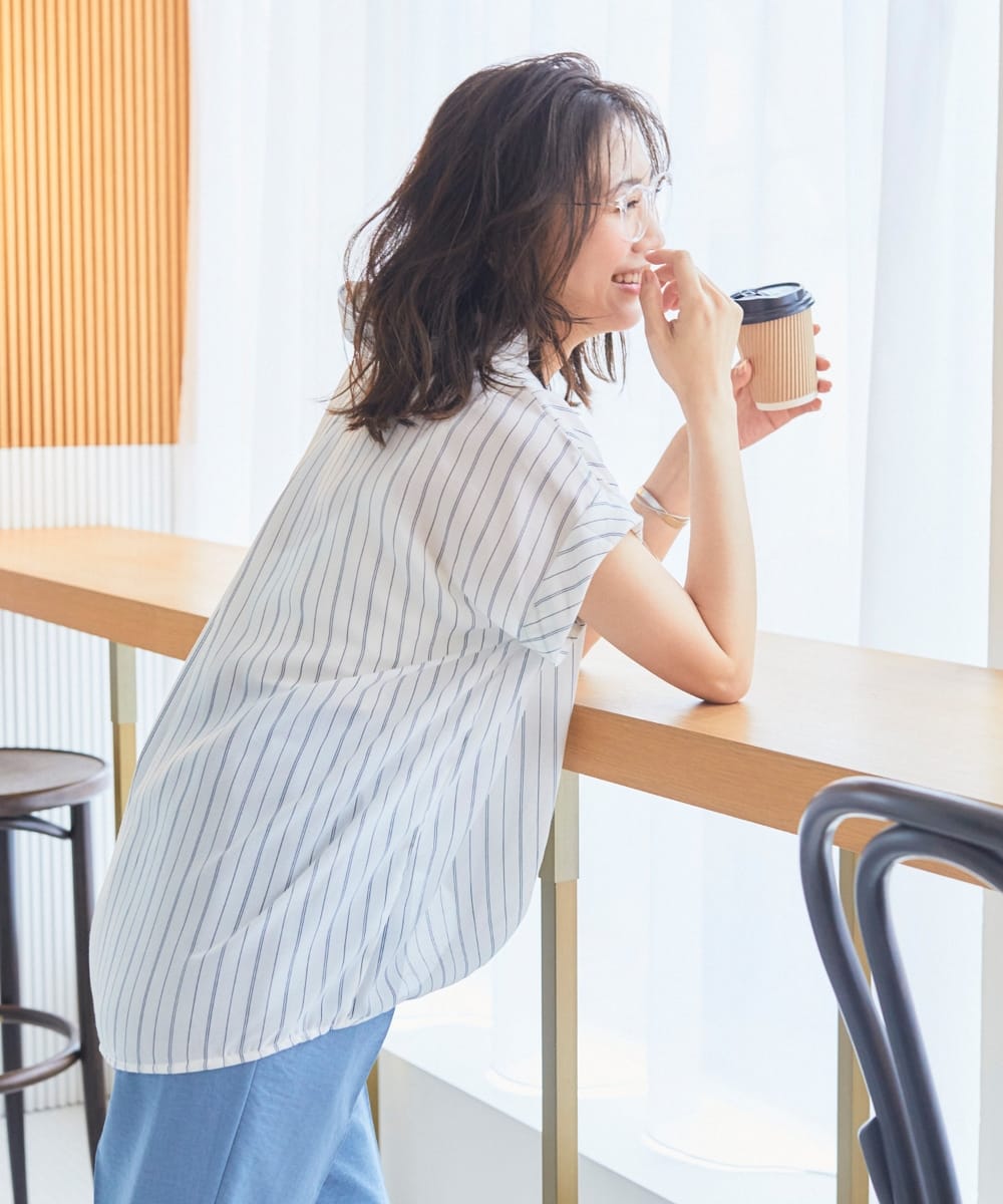 シャツ活／ツイルフロントタックブラウス ストライプ（オフ）を着用して外を見ている女性