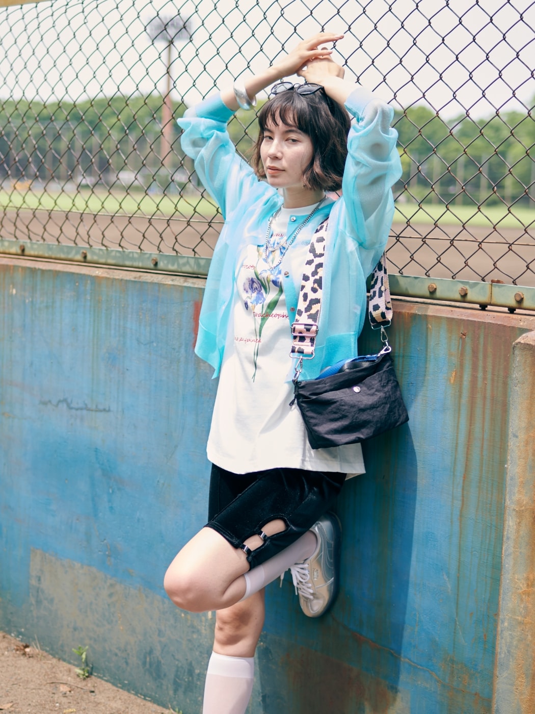 シアーニットカーディガンとアイリスプリントチュニックTシャツとニットハーフレギンスとクラウンバンドサングラスを着用した女性１