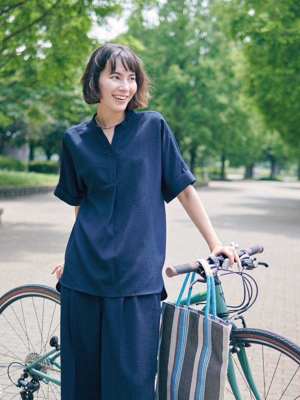リネンライクシャツ【接触冷感】とリネンライクパンツ【接触冷感】とストライプスクエアトートバッグを着用した女性１