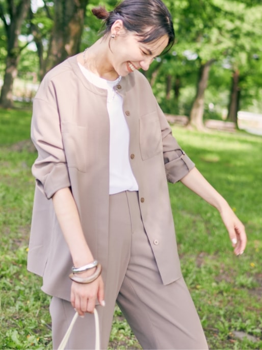 【美モーション】ストレッチノーカラーシャツジャケット【接触冷感・UVカット】とシアーレイヤードロゴTシャツと【美モーション】トリニータストレッチワイドパンツ【接触冷感・UVカット】を着用した女性２