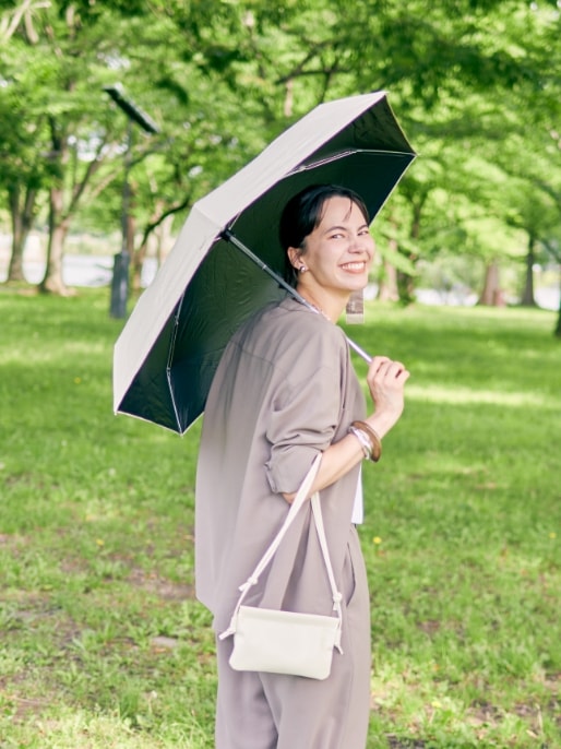 【美モーション】ストレッチノーカラーシャツジャケット【接触冷感・UVカット】とシアーレイヤードロゴTシャツと【美モーション】トリニータストレッチワイドパンツ【接触冷感・UVカット】と【Wpc.】日傘折りたたみ 遮光ノーブルベーシック ミニ【完全遮光100％ 完全UVカット率100％生地 コンパクト 晴雨兼用】を着用した女性