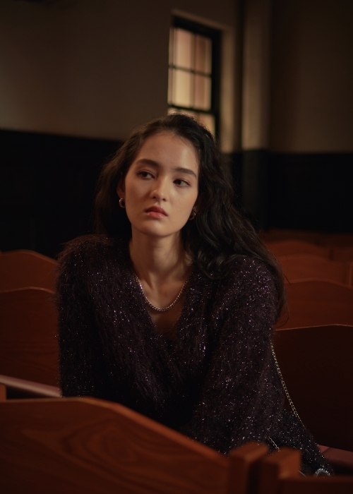 ブラウンのラメフェザーVネックカーディガン・ブラックのヴィーガンレザーハーフパンツを着用した女性の画像--2