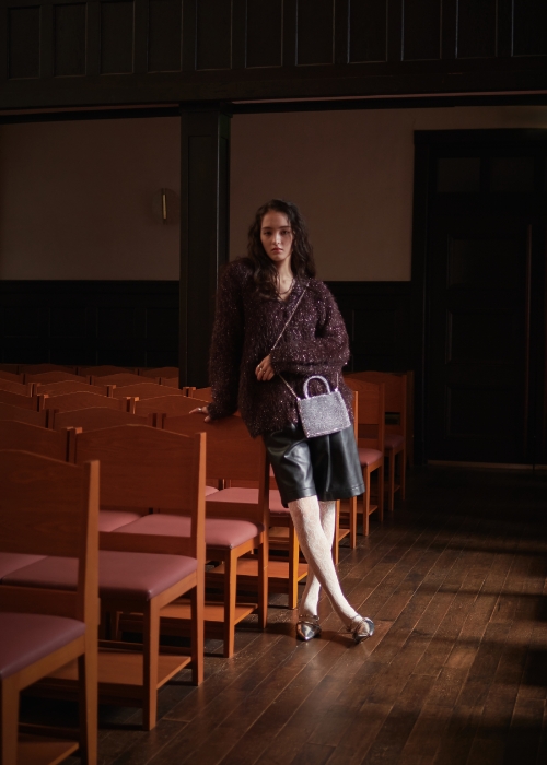 ブラウンのラメフェザーVネックカーディガン・ブラックのヴィーガンレザーハーフパンツを着用した女性の画像--3