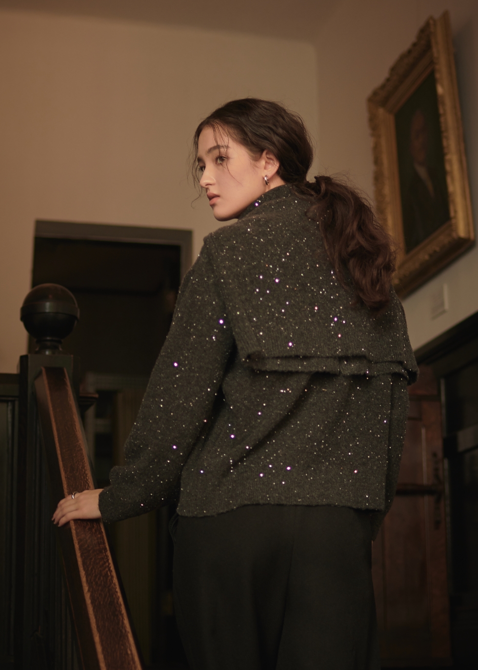 チャコールグレーのスパンコールニットカーディガン・チャコールグレーのスパンコールニットプルオーバー・ブラックのウーリッシュタックストレートパンツを着用した女性の後ろ姿の画像