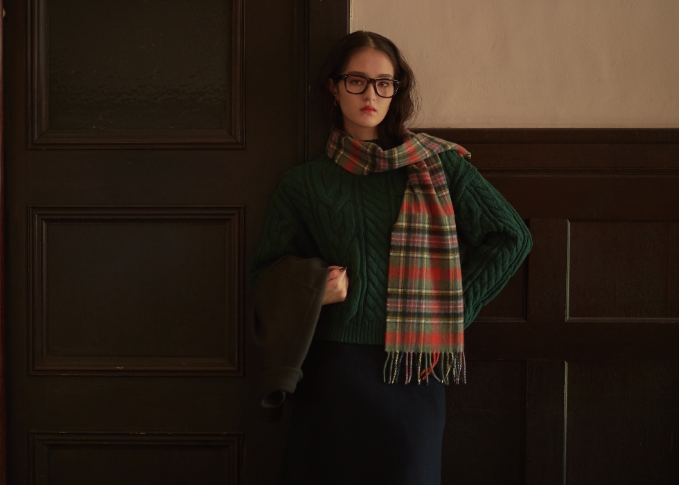 グレージュの丸衿ウールジャケット・ダークグリーンのケーブル編みハイネックニット・ネイビーのウールメルトン台形スカート・オレンジのロキャロンカシミアチェック柄マフラーを着用した女性の画像--2