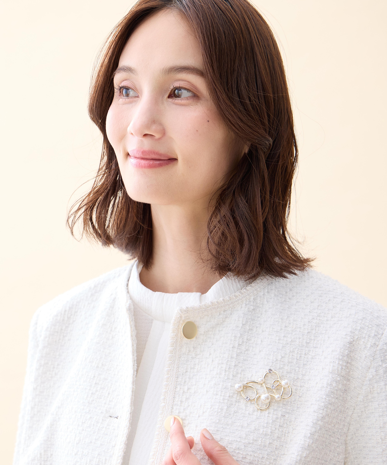A/C DESIGN BY ALPHA CUBIC パールモチーフブローチを着用した女性