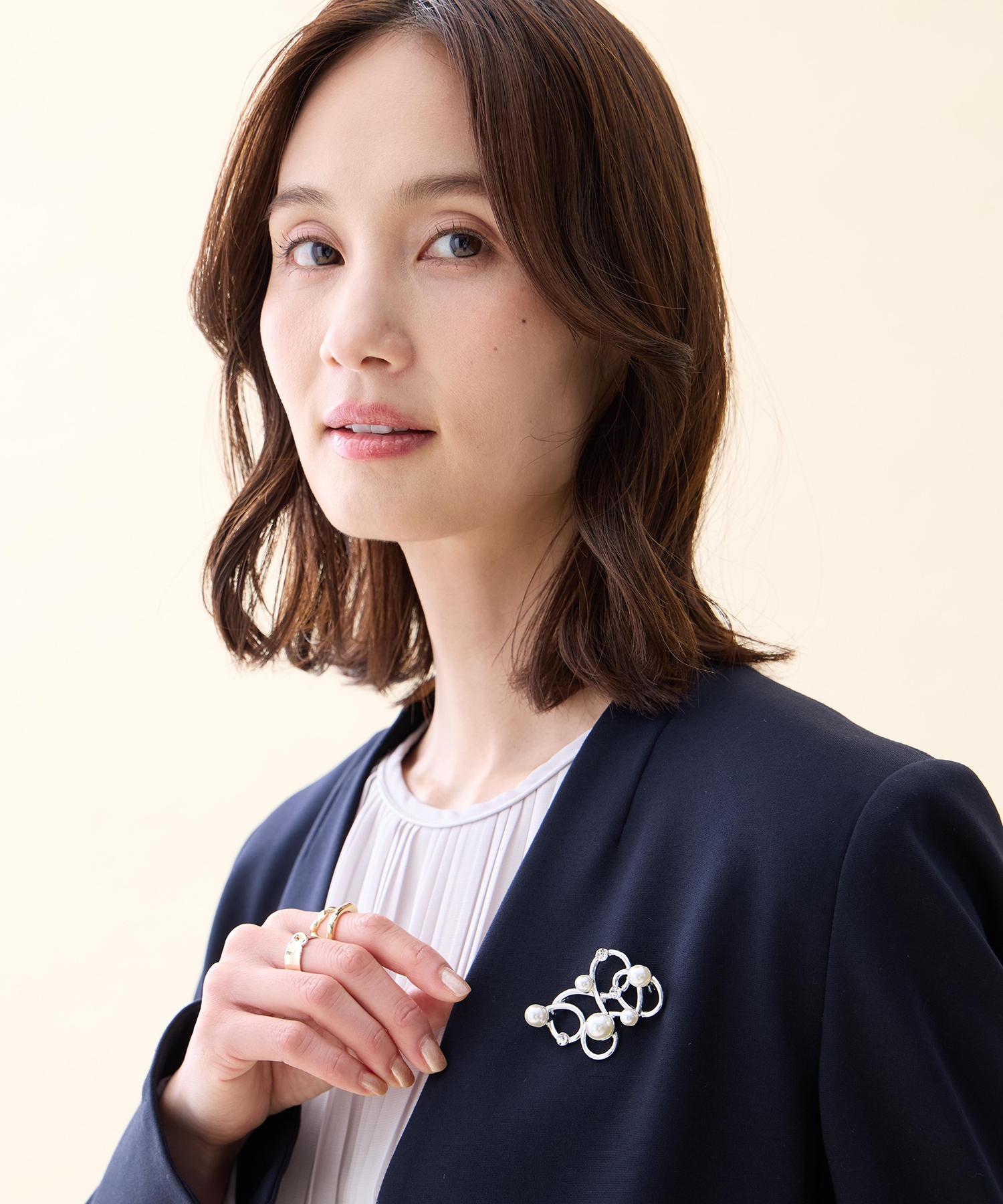 A/C DESIGN BY ALPHA CUBIC パールモチーフブローチを着用した女性