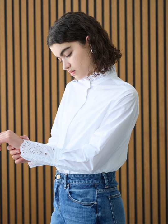 カットワーク刺繍フリルシャツを着用した女性