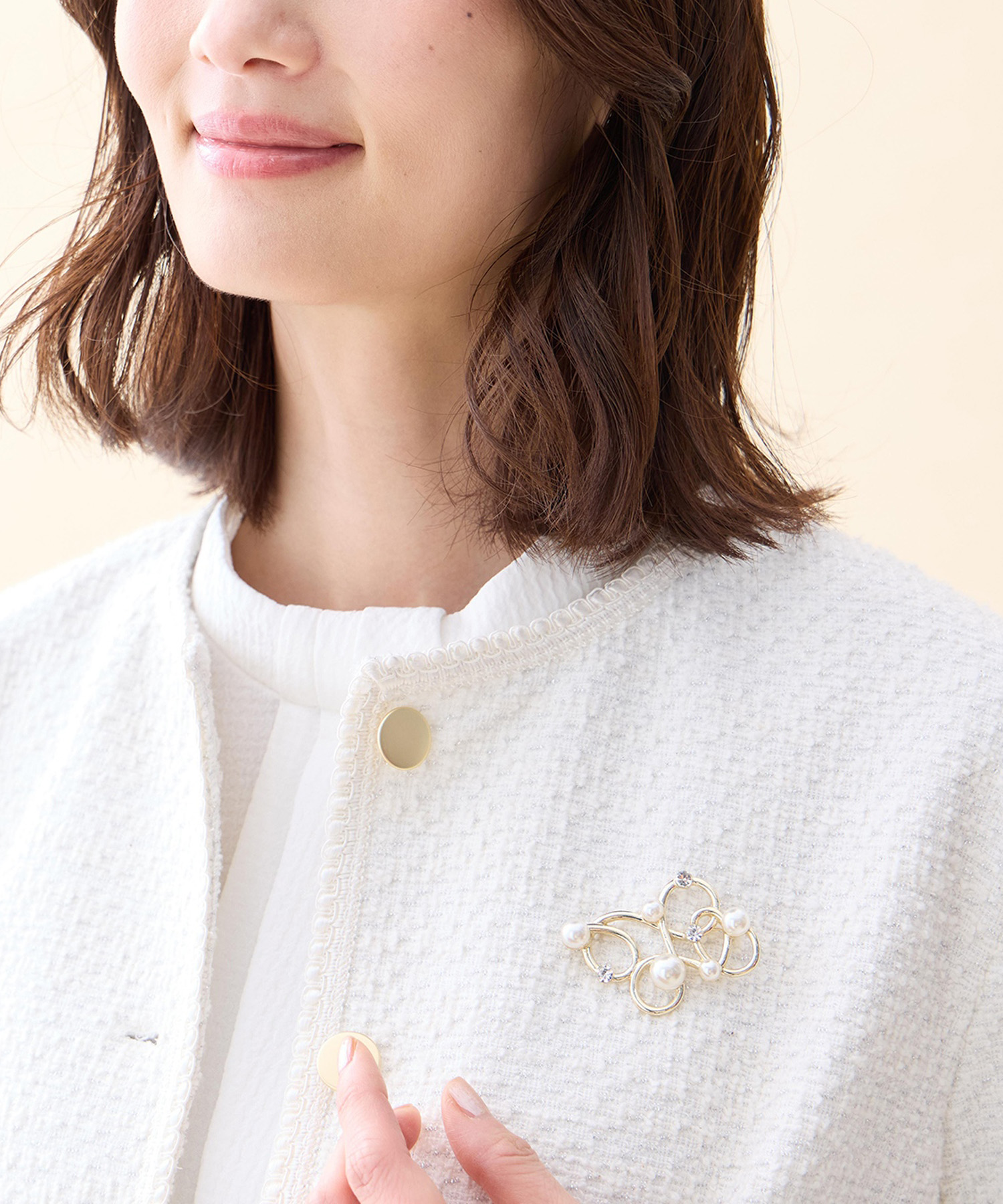 A/C DESIGN BY ALPHA CUBIC パールモチーフブローチを着用した女性