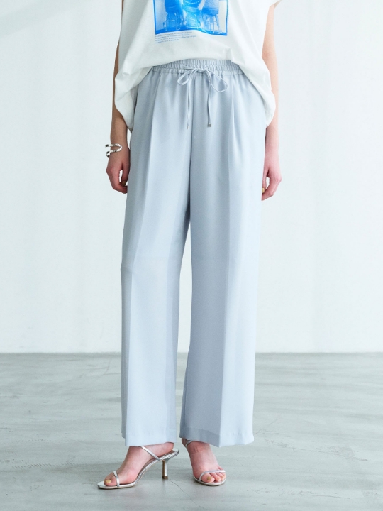 サックスのバックサテンストレッチイージーパンツを着用した女性